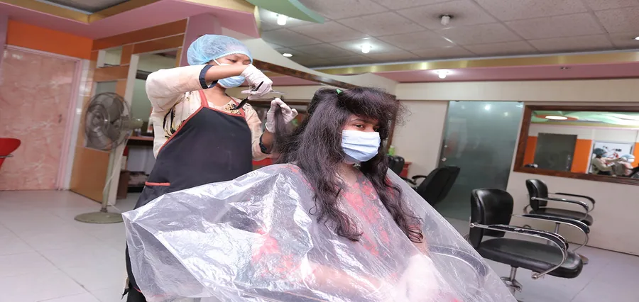 A customer’s hair being cut and styled at the mirror