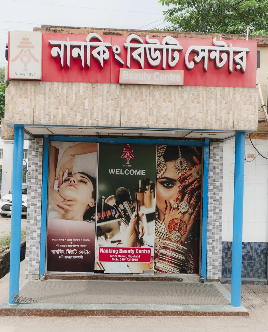 The entrance of Nanking Beauty Center under its red Bangla sign, with bridal and make-up posters on the glass doors