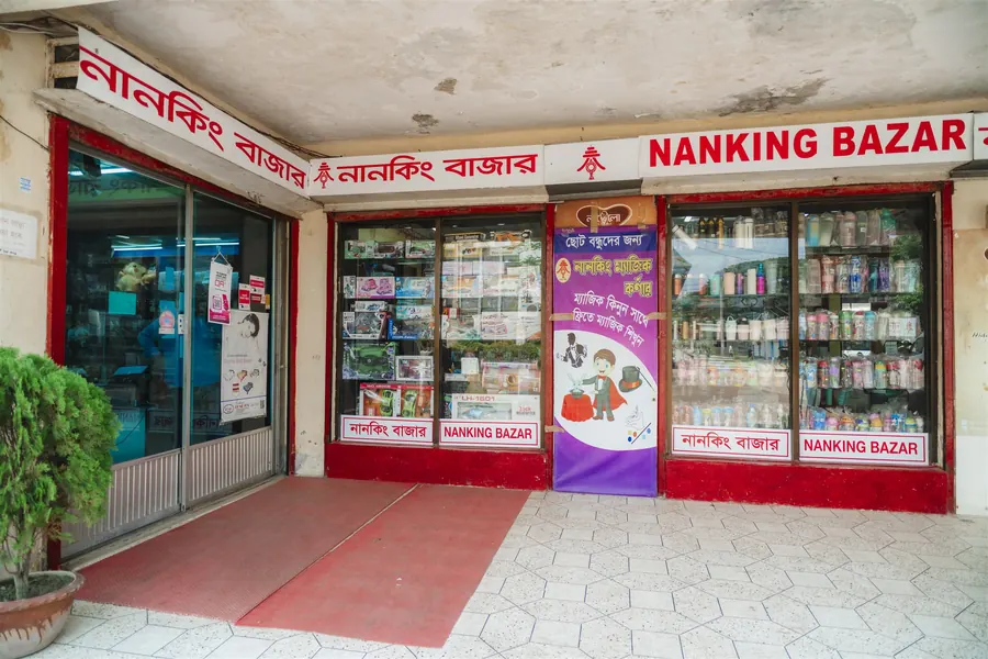 The glass entrance of Nanking Bazar under a red sign in Bangla and English
