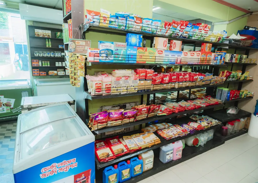 Shelves stacked with bags of rice, flour and noodles beside a chest freezer