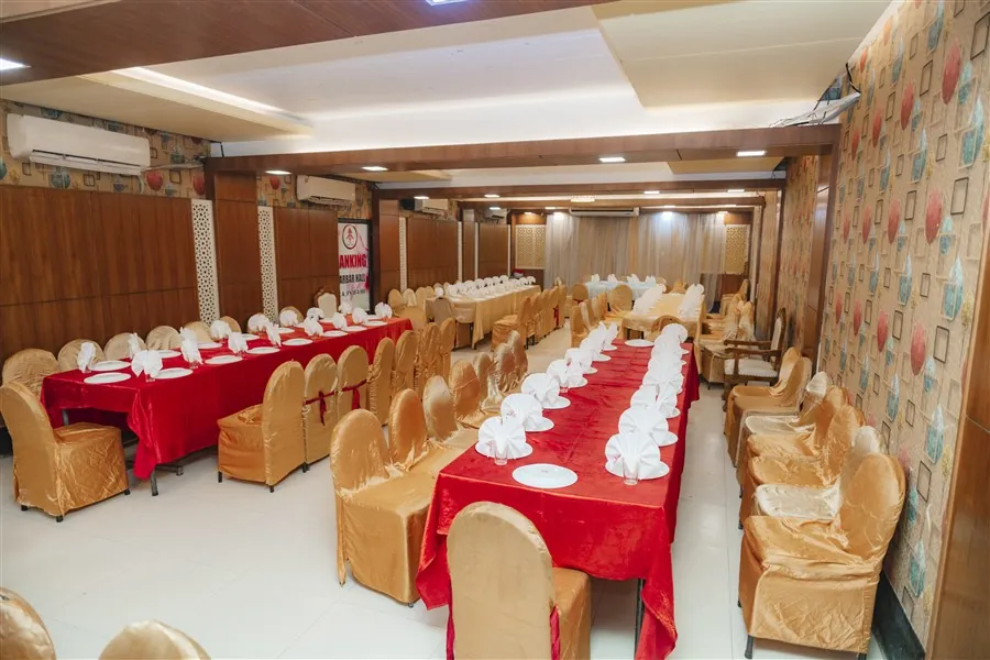 Long dining tables with red cloths and gold chair covers in the Darbar Hall
